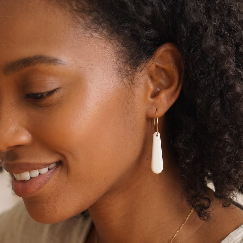 Boucles d'oreilles créoles Aube en porcelaine blanche portées.