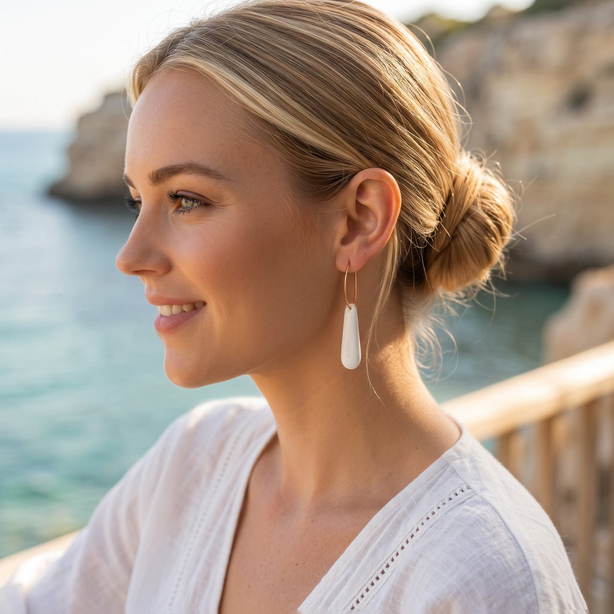 jeune femme portant les boucles d'oreilles créoles Aube en porcelaine blanche.