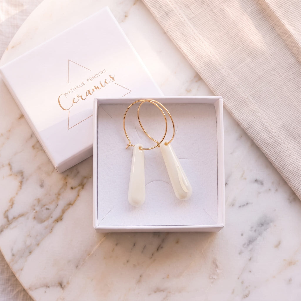 Écrin blanc Nathalie Penders contenant les boucles d'oreilles créoles Aube en porcelaine blanche.