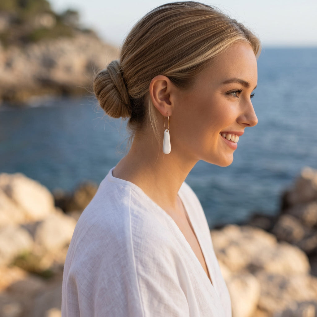 jeune femme portant les boucles d'oreilles créoles Aube en porcelaine blanche.