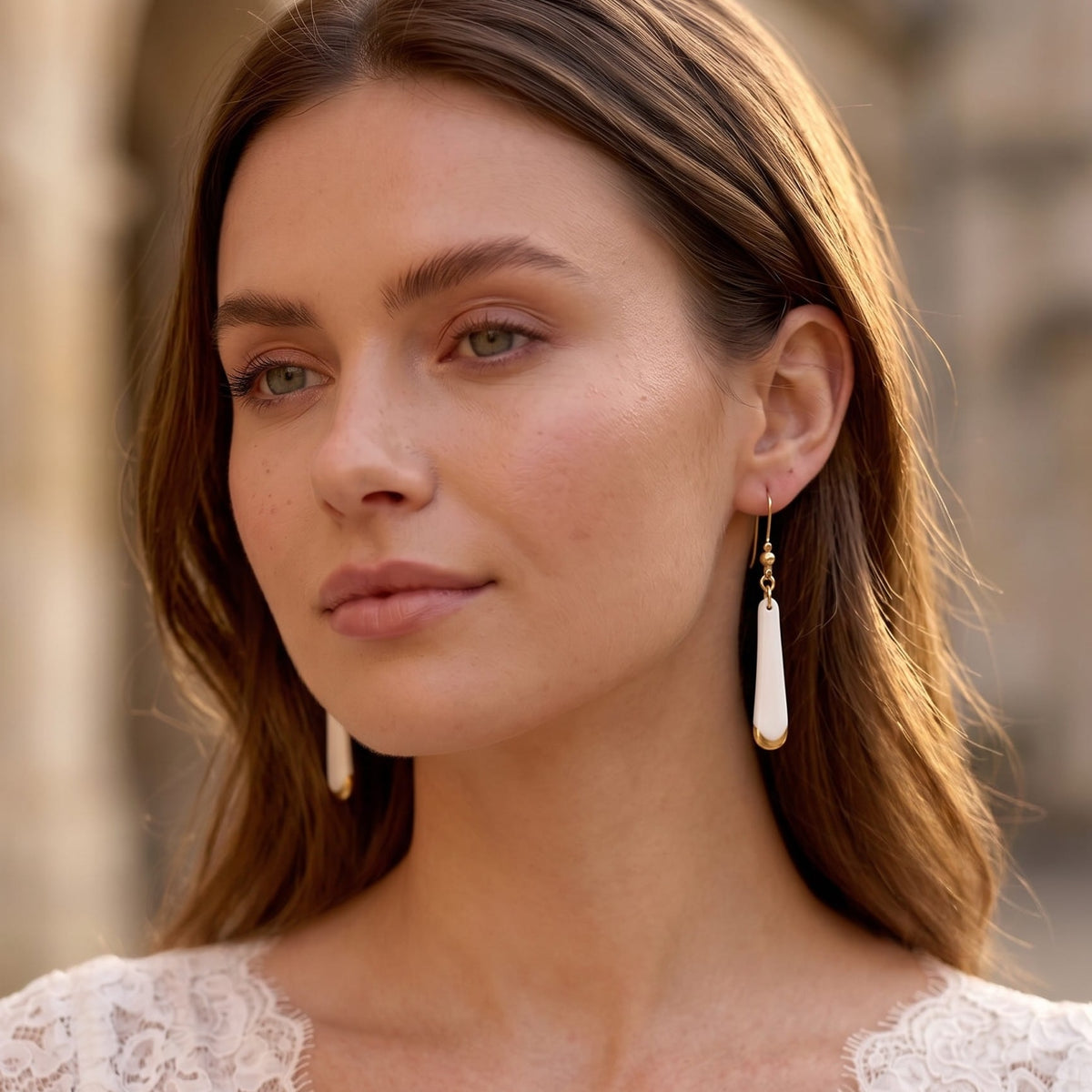Jeune mariée portant des boucles d'oreilles pendantes Aube en porcelaine blanche et or