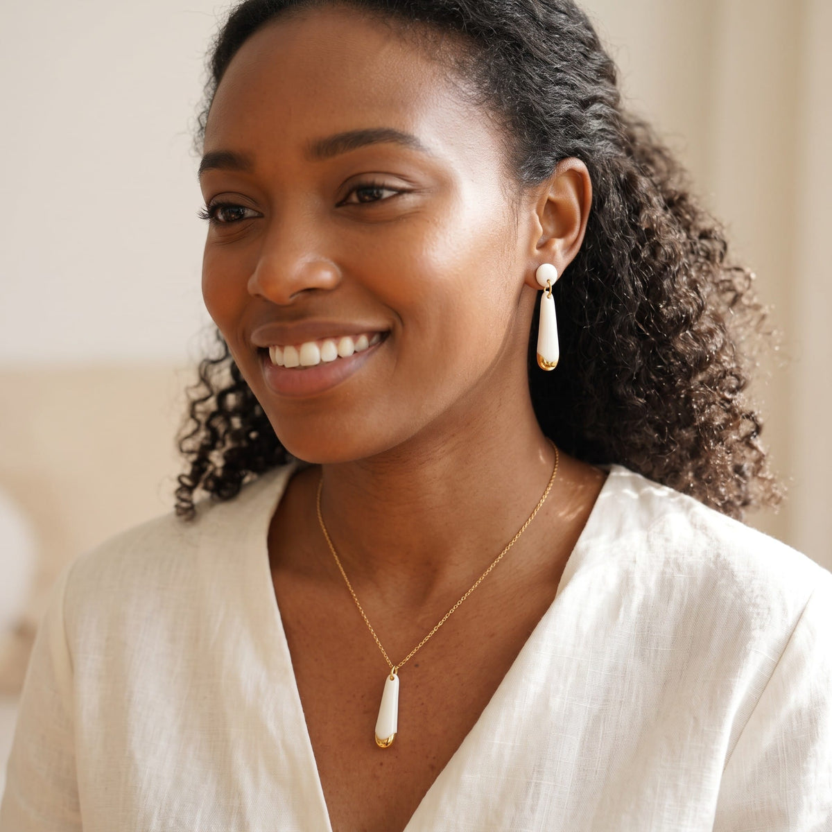 Boucles d'oreilles en céramique et collier assorti portés par une jeune femme élégante.