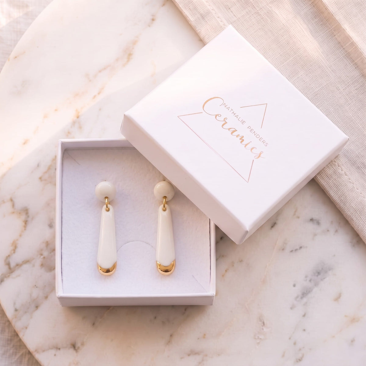 Boucles d'oreilles puces Aube en porcelaine blanche et or dans leur écrin